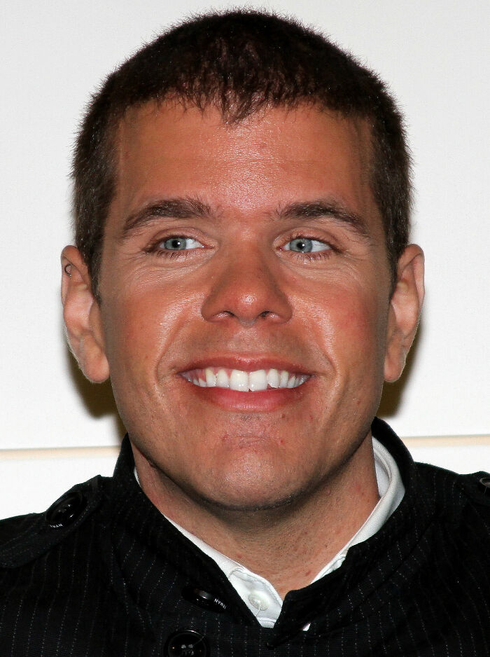 Perez Hilton smiling at an event, wearing a dark jacket and showing a confident expression in a close-up portrait.