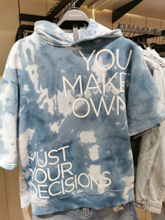 Blue tie-dye hoodie with a confusing text design, showcasing hilariously bad T-shirt designs in a clothing store.