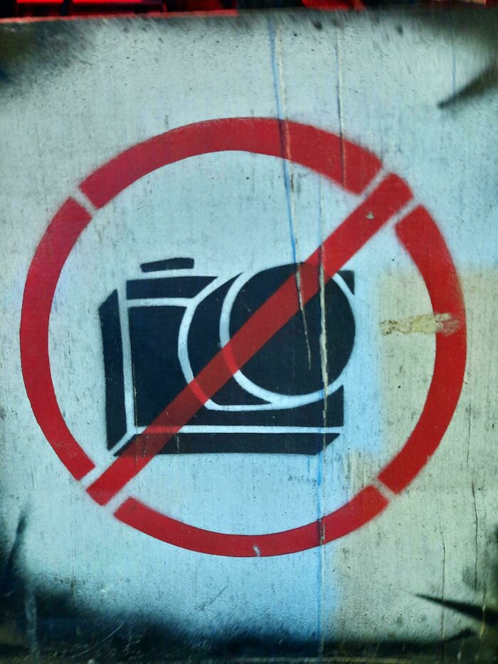 No photography symbol painted on a weathered wall, representing first-world anarchists expressing resistance.