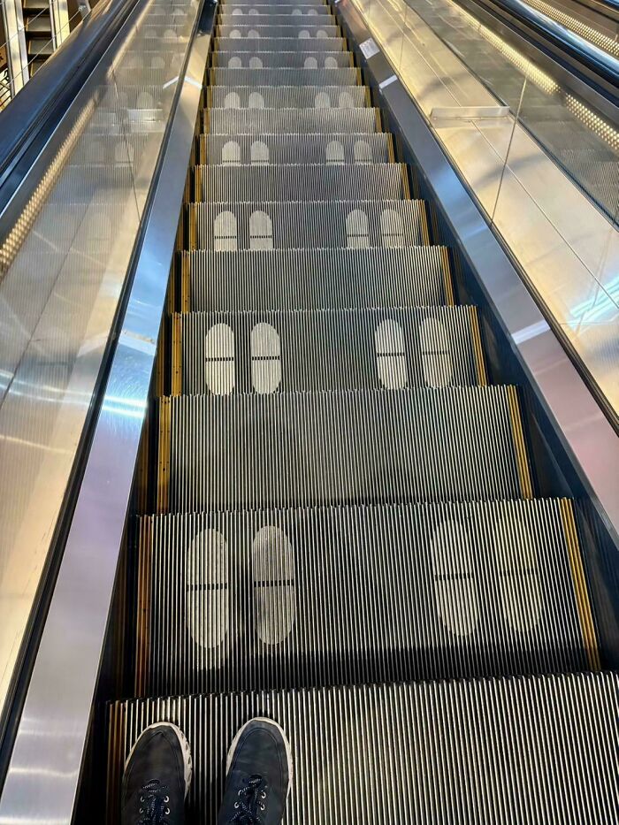 Escalator steps with painted footprints showing where to stand, representing ungovernable behavior in public spaces.