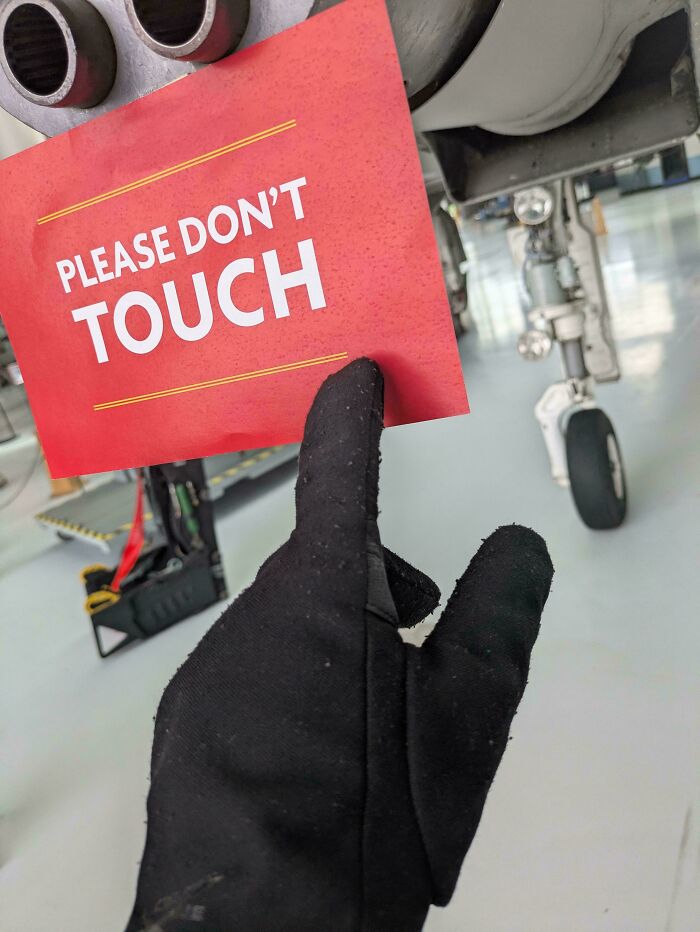 Hand in black glove reaching to touch a red sign that reads "Please Don't Touch," symbolizing first-world anarchists being ungovernable.