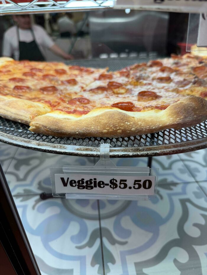 Pepperoni pizza slice on a display rack with a price tag in a restaurant, first-world anarchists style.