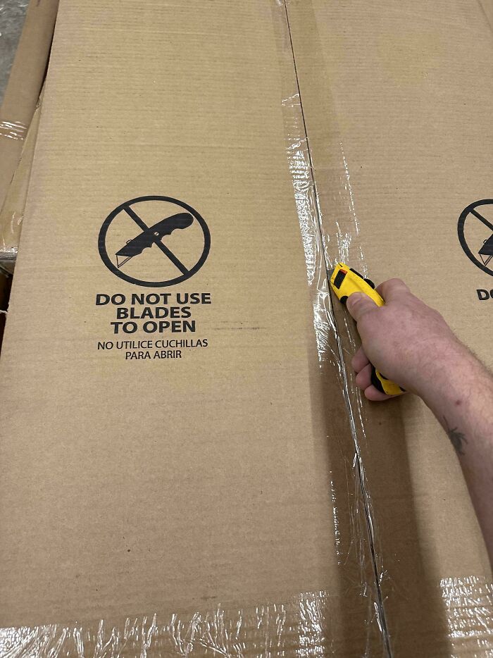 A person using a blade to open cardboard boxes despite a clear warning, illustrating first-world anarchists defying rules.