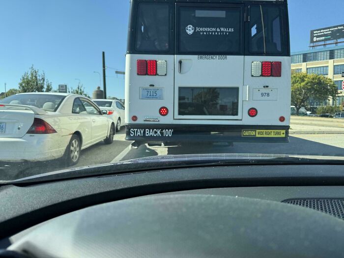 View from inside a car stuck in traffic behind a Johnson & Wales University bus, representing first-world anarchists defying norms.