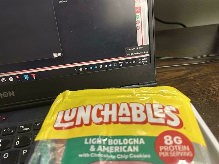 Packaged Lunchables with light bologna and American cheese on a desk by a laptop, capturing modern snack culture.
