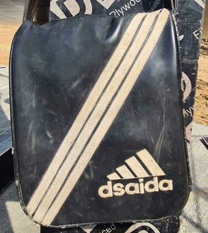 Black bag with three stripes and a logo reading dsaida, showcasing a shameless designer copy of famous brand style.