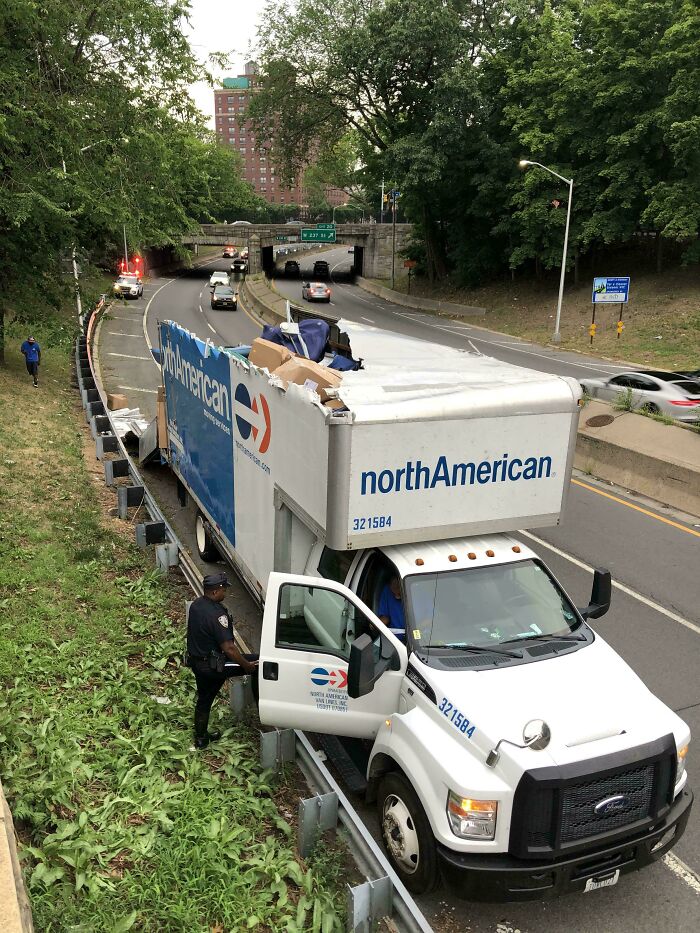 Overhead view of an accident: a North American moving truck crashed into a guardrail with items spilling out. Fails and accidents.