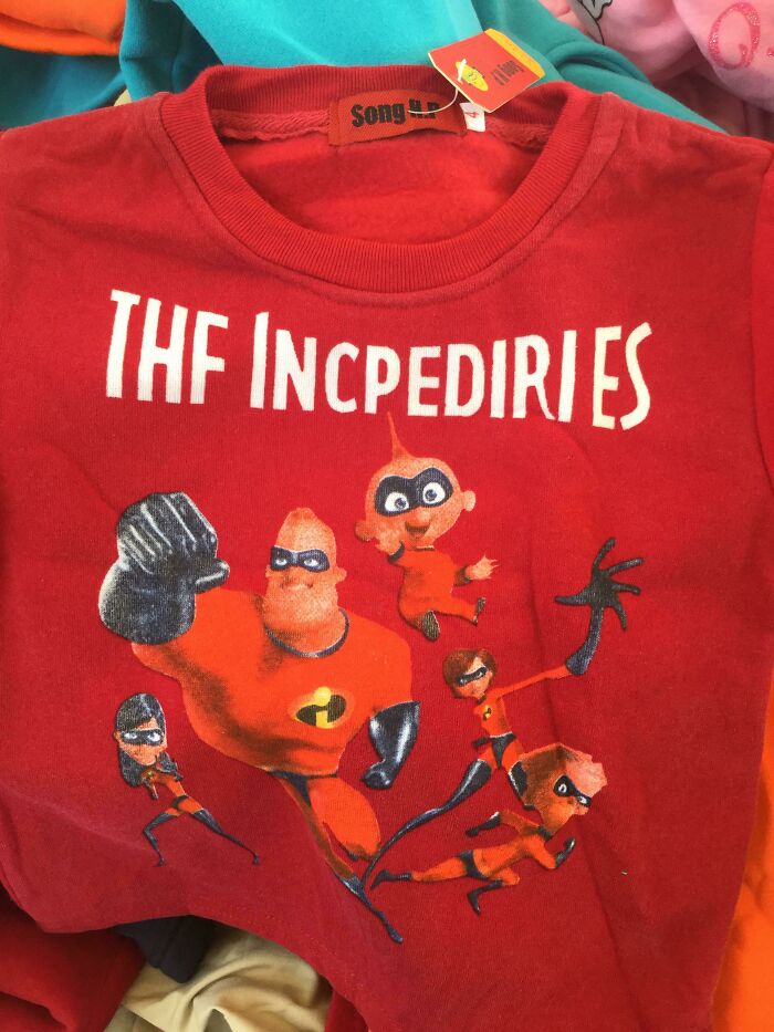 Red t-shirt with hilariously bad misspelled character design parody showing "The Incpediries" and superhero figures.