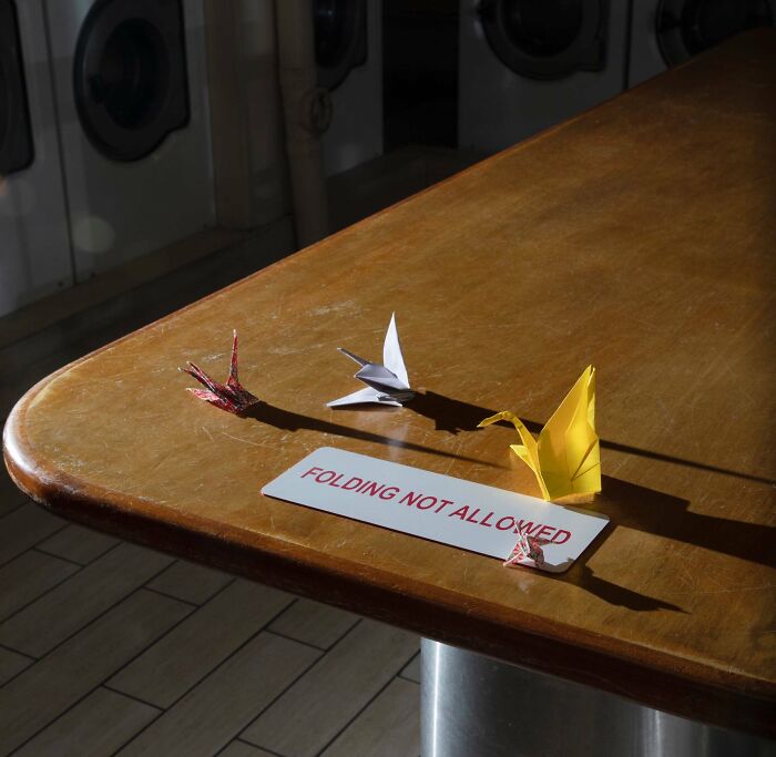 Origami cranes placed on a table with a folding not allowed sign, showing mild vandalism humor and creativity.
