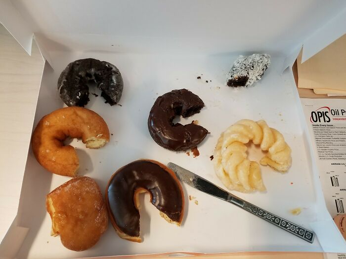 Assorted partially eaten donuts in a box with a knife, illustrating ungovernable anarchists' bold and fearless spirit.