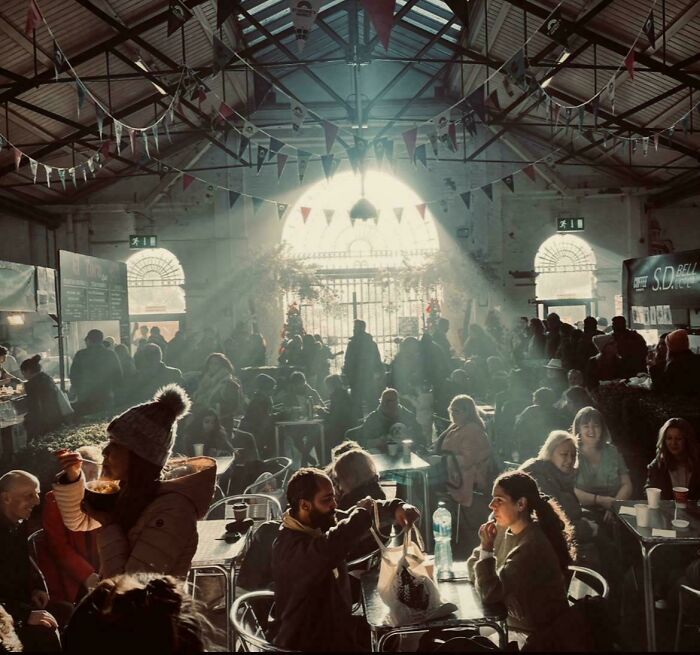 Sunlight streaming through windows onto crowds in a large hall with Accidental Renaissance lighting