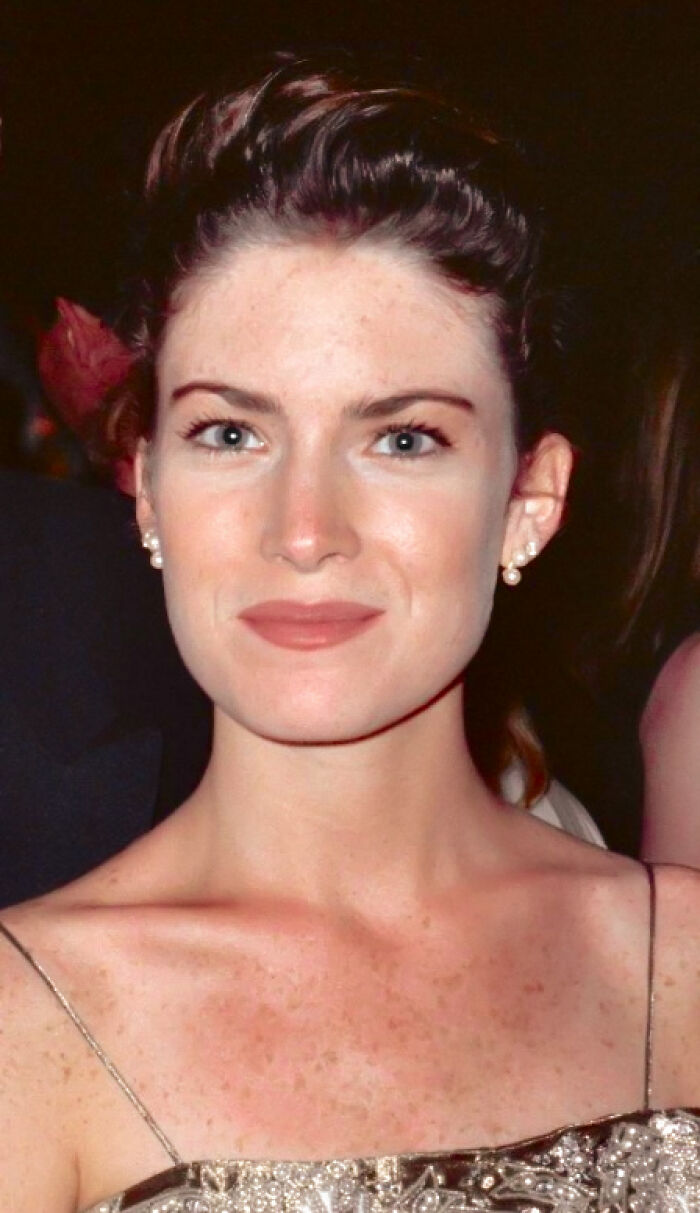 Lara Flynn Boyle smiling at an event, wearing pearl earrings and a sparkly dress, highlighting her career in acting.