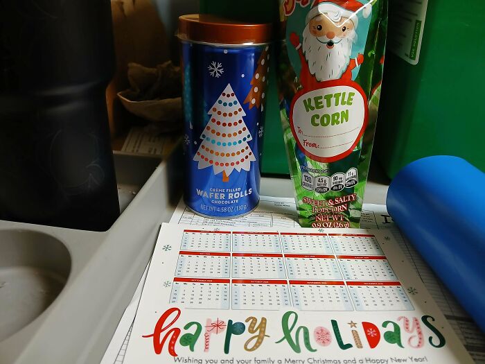 Holiday treats and calendar on a cluttered office desk reflecting workplace culture and employee experience.