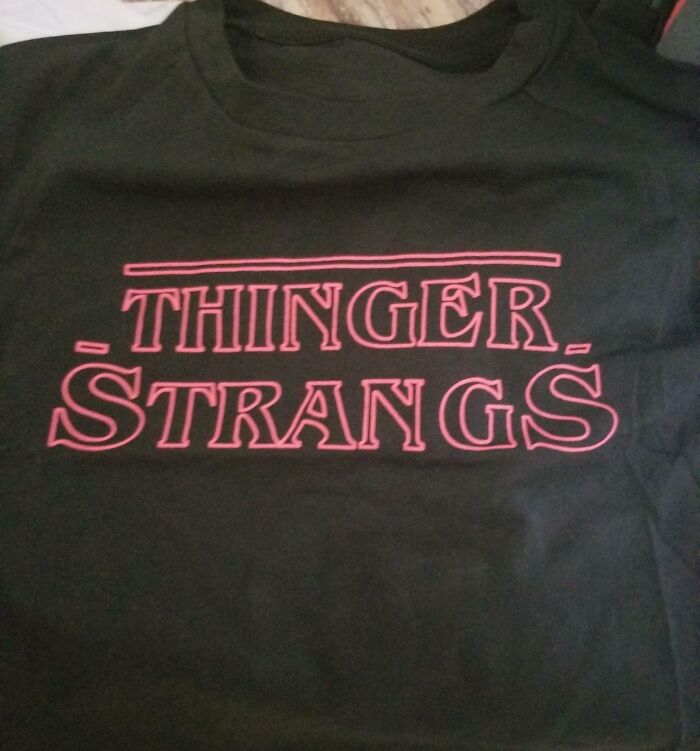 Black t-shirt with a hilariously bad design featuring the misspelled phrase Thinger Strangs in red letters.