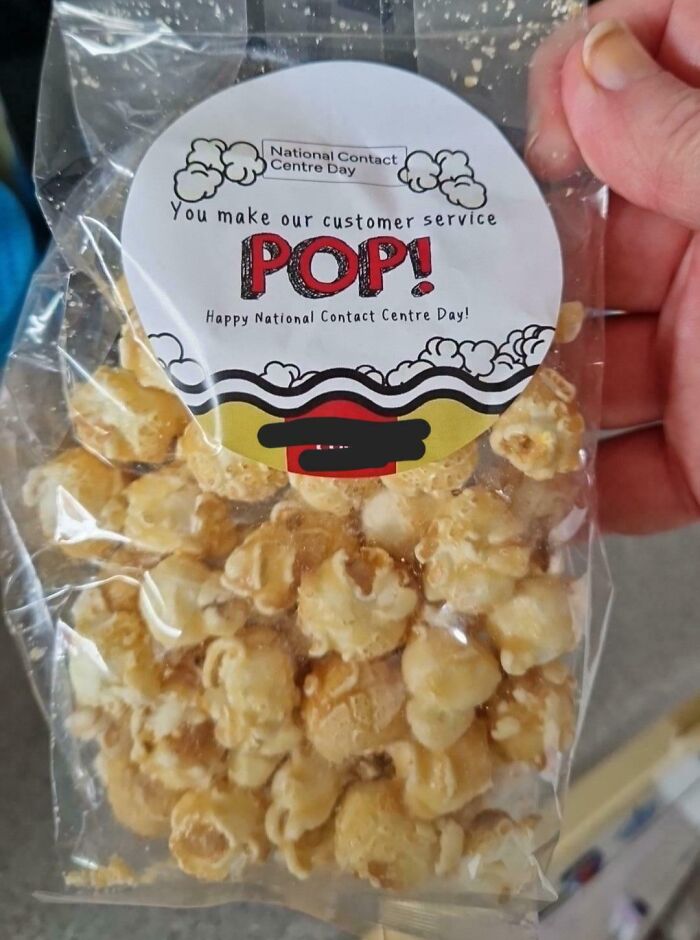 Hand holding a small popcorn bag with a label celebrating National Contact Centre Day and customer service appreciation.