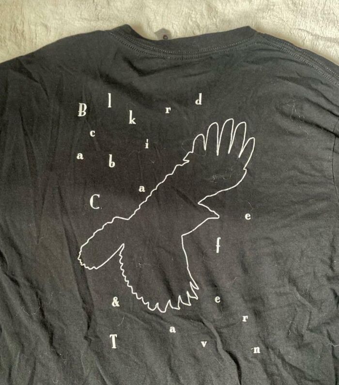 Black T-shirt with a bird outline and scattered letters, showcasing one of the hilariously bad T-shirt designs.