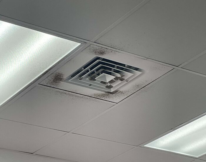 Dirty air vent on office ceiling with stained ceiling tiles illustrating poor workplace conditions and why no one wants to work anymore