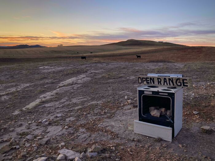 Open stove with sign reading open range in rural landscape at sunset, capturing essence of US states scenery.
