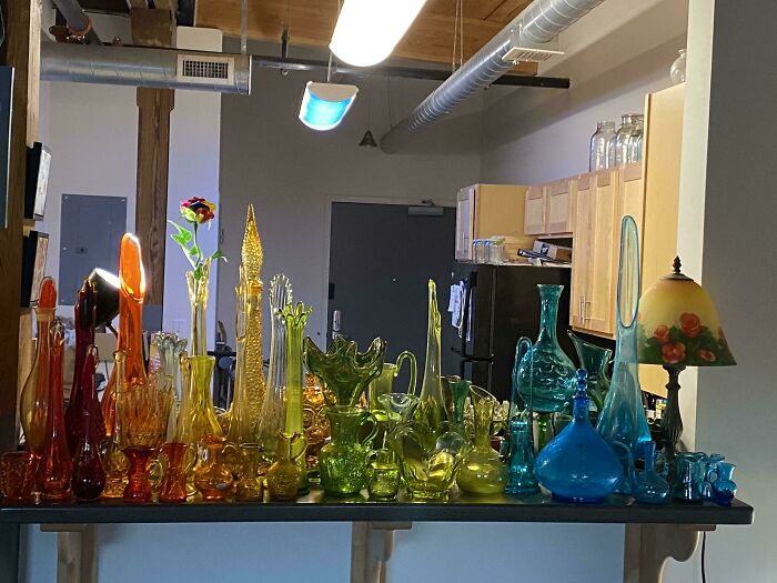 Colorful cool and creative glass items in various shapes and sizes displayed on a shelf in a modern home interior.