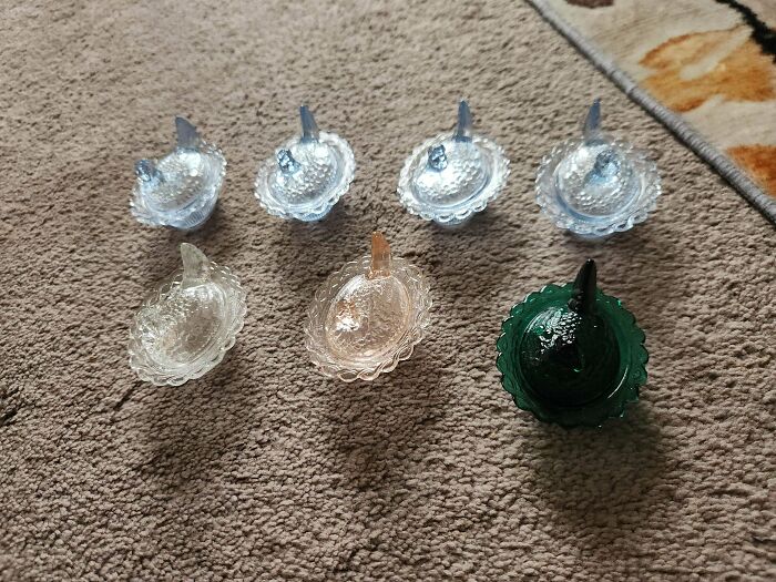 Assorted cool and creative glass items shaped like birds displayed on a carpeted floor for home decor.