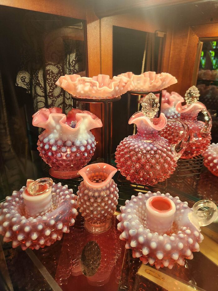 Collection of creative hobnail glass items in pink and white hues displayed on a wooden shelf at home.