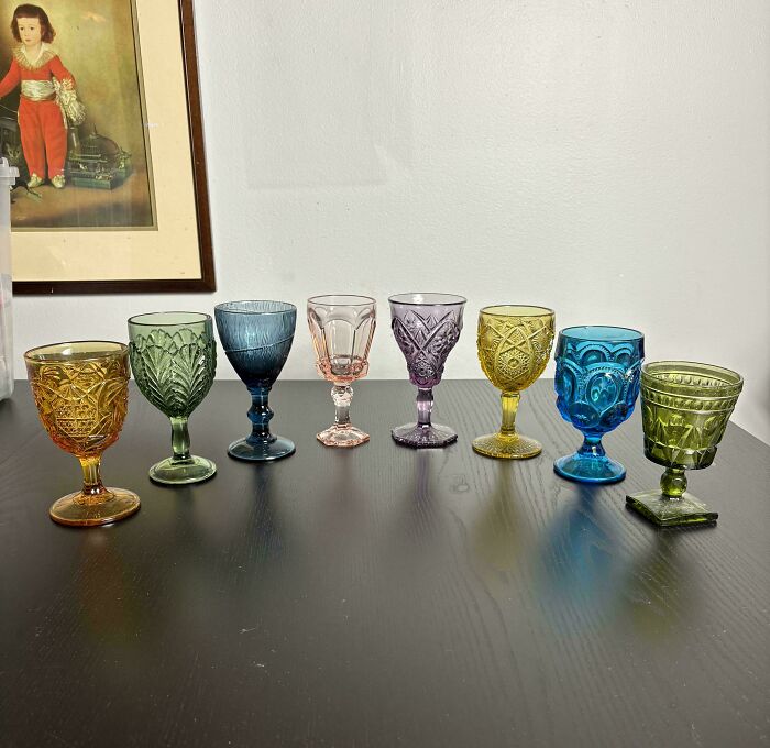 A collection of colorful and creative vintage glass items arranged on a dark wooden surface at home.