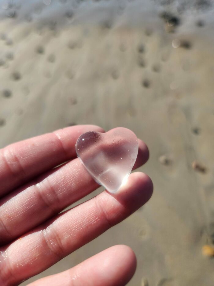 Clear heart-shaped glass item held between fingers, showcasing a cool and creative glass item for home decor.