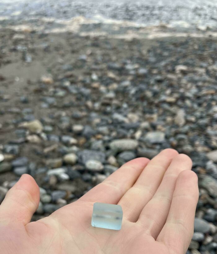 Hand holding a small smooth glass item found on a rocky beach, a cool and creative glass item for home decoration.