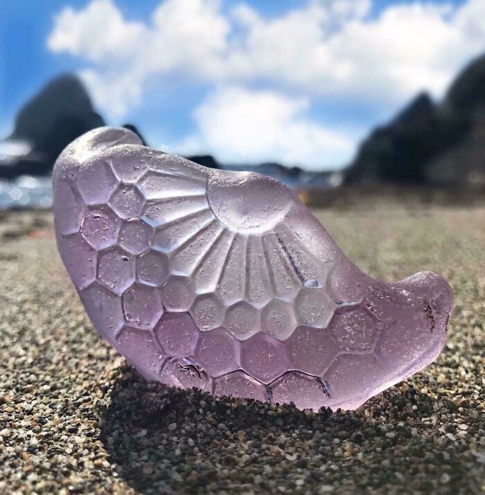 Purple decorative glass item with honeycomb and sunburst patterns on a sandy beach, a cool and creative glass item.