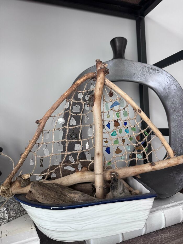 Creative glass items in a handmade sailboat decoration with colorful glass pieces and driftwood for home decor.