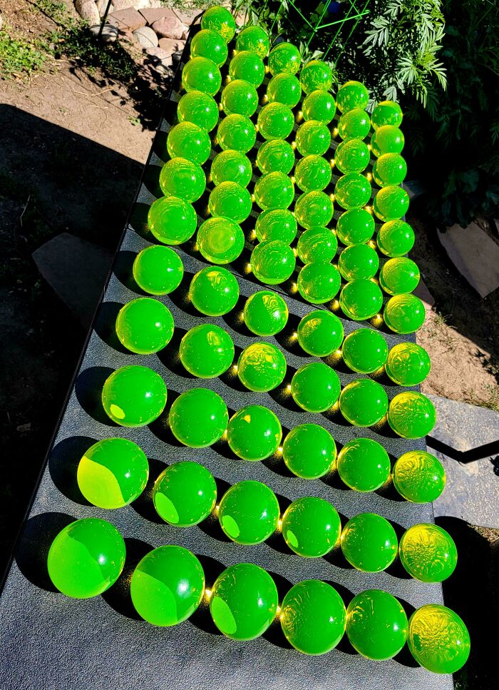 Bright green glass spheres arranged in rows outdoors, showcasing creative and cool glass items for home decor.