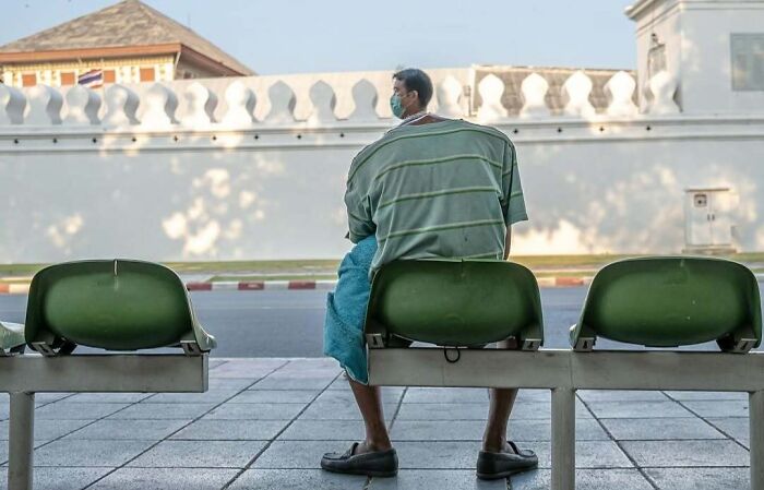 Man with distorted upper body sitting on a bench outdoors, one of the unedited photos that might mess with your brain.