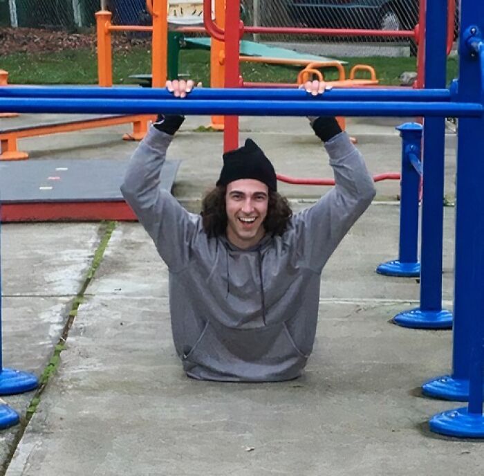 Man hanging from playground bars with no visible legs in a confusing photo that might mess with your brain.
