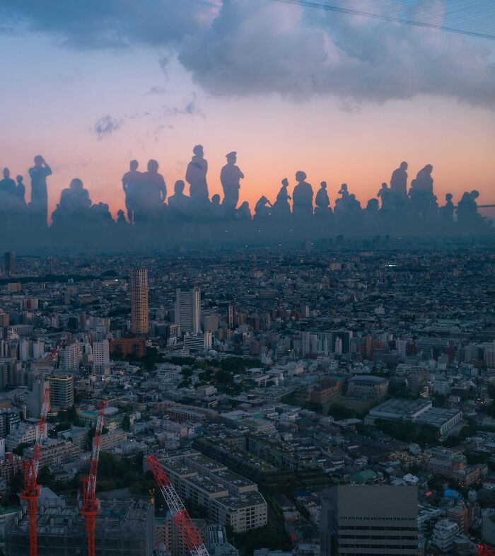 Silhouettes of people appear floating above a cityscape at sunset in an unedited photo that challenges perception and brain focus.