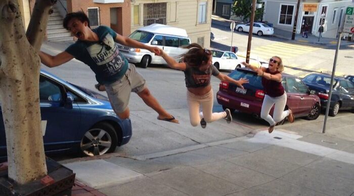 Three people pulling off creative and hilarious poses while appearing to float above a sloped urban street scene.