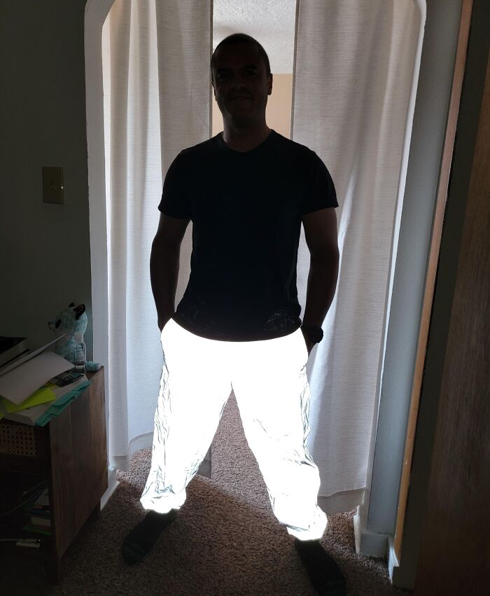Person wearing reflective pants glowing intensely in a dim room, an unedited photo that might mess with your brain.