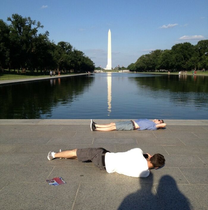 Photographer capturing image of man lying near reflecting pool with Washington Monument in background, showcasing essence of US states.
