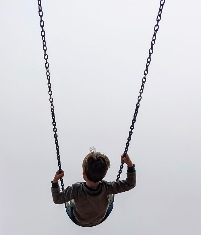 Child on a swing against an empty sky, one of the unedited photos that might mess with your already tired brain.