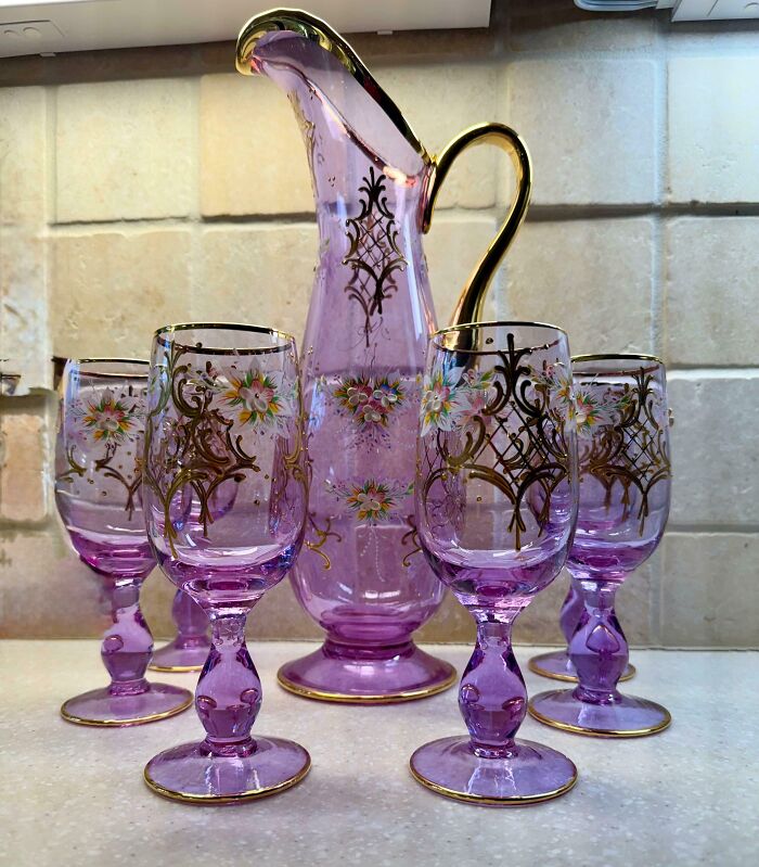 Purple glass pitcher and matching floral decorated glasses with gold accents, a creative glass item for your home collection.