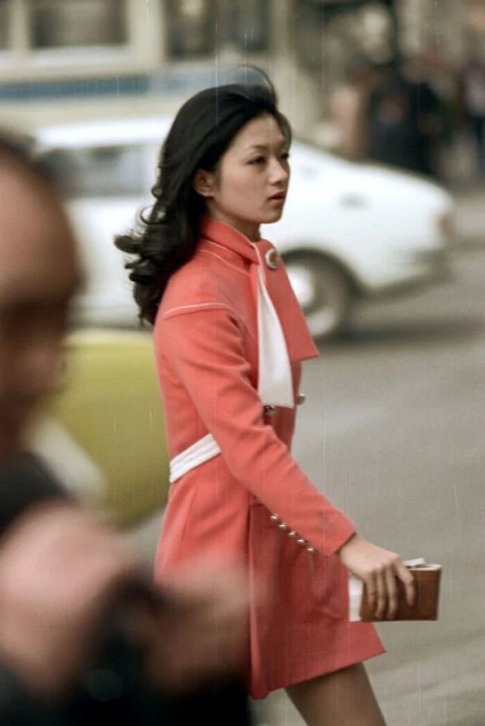 A candid old photo of a woman walking on a street, capturing fashion and life from generations ago.