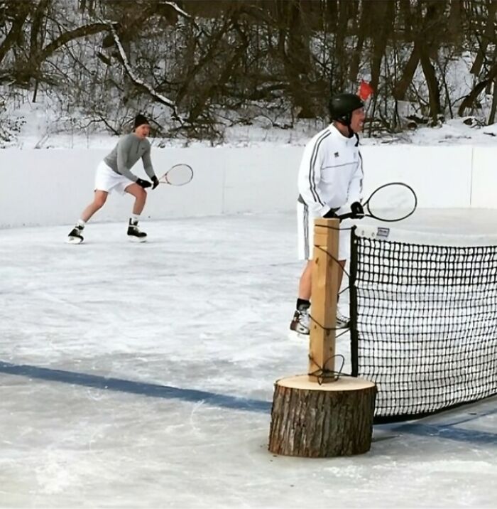 Two men playing tennis on an outdoor ice rink in winter, capturing unique and fun state essence in the US.