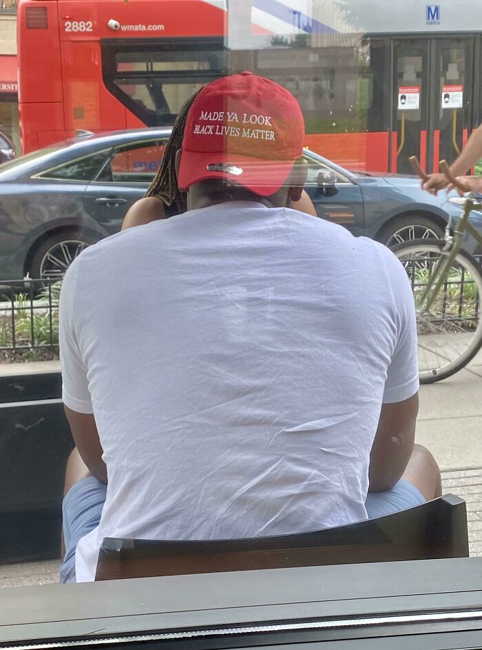 Man wearing a red hat with a message sitting outdoors with vehicles and a cyclist in the background, showing seemingly innocent posts.