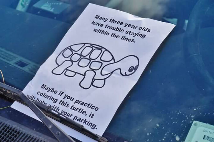 Paper with funny advice and a turtle drawing placed under a car windshield wiper on a blue car windshield.