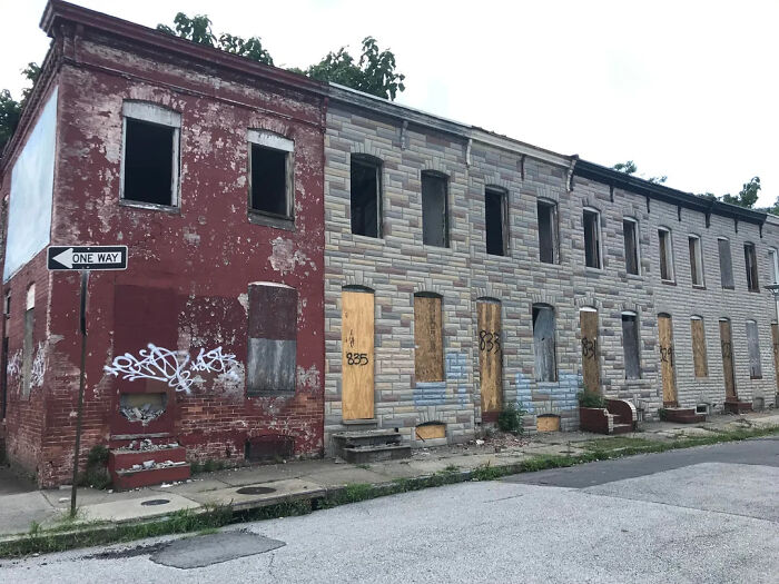 Abandoned urban row houses boarded up with peeling paint and graffiti in urban hell scene