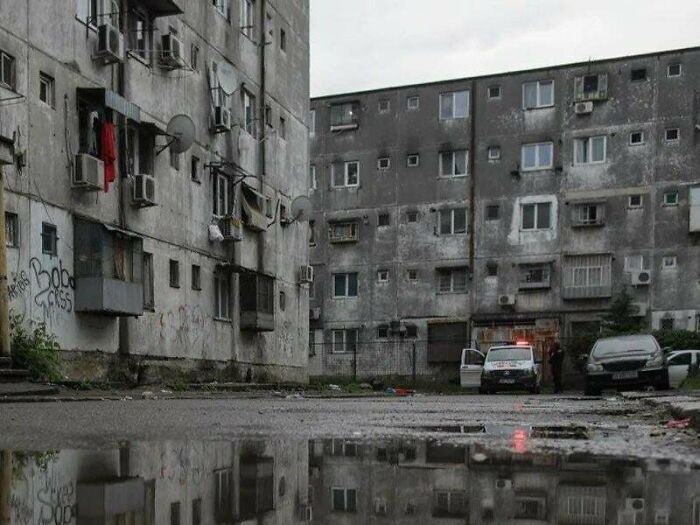 Dilapidated apartment buildings with graffiti and police car in urban hell neighborhood
