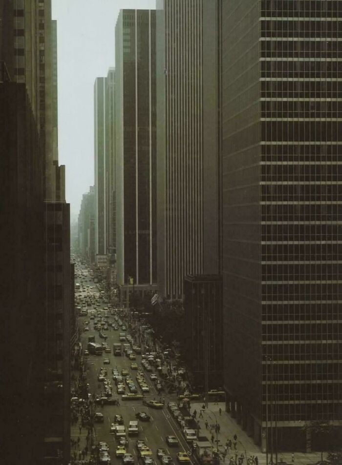 Traffic-filled street lined with tall skyscrapers in urban hell cityscape