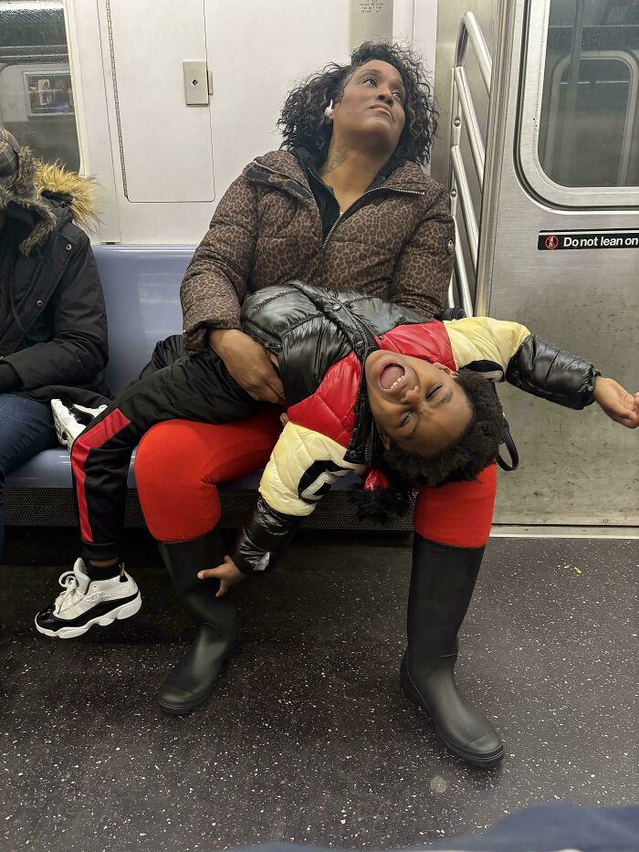 Tired mother holding screaming toddler on subway in an Accidental Renaissance moment