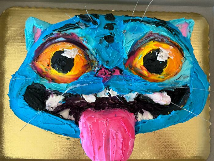 Blue cat face cake with vibrant eyes and pink tongue dessert