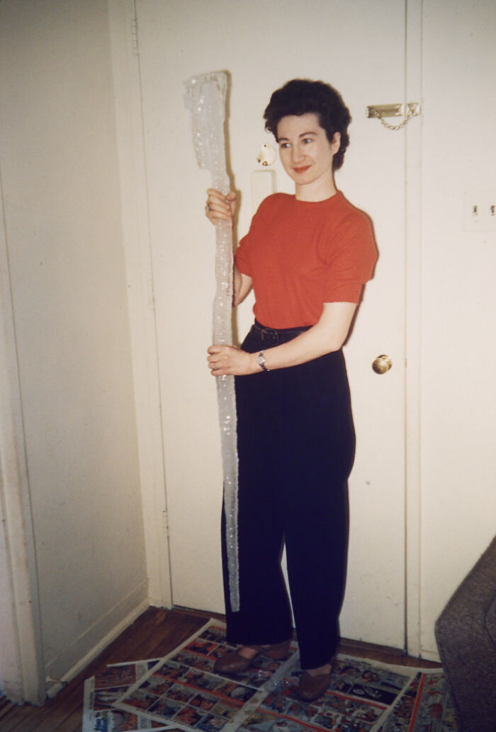 A candid old photo of a woman holding a large icicle, revealing an interesting moment generations ago.