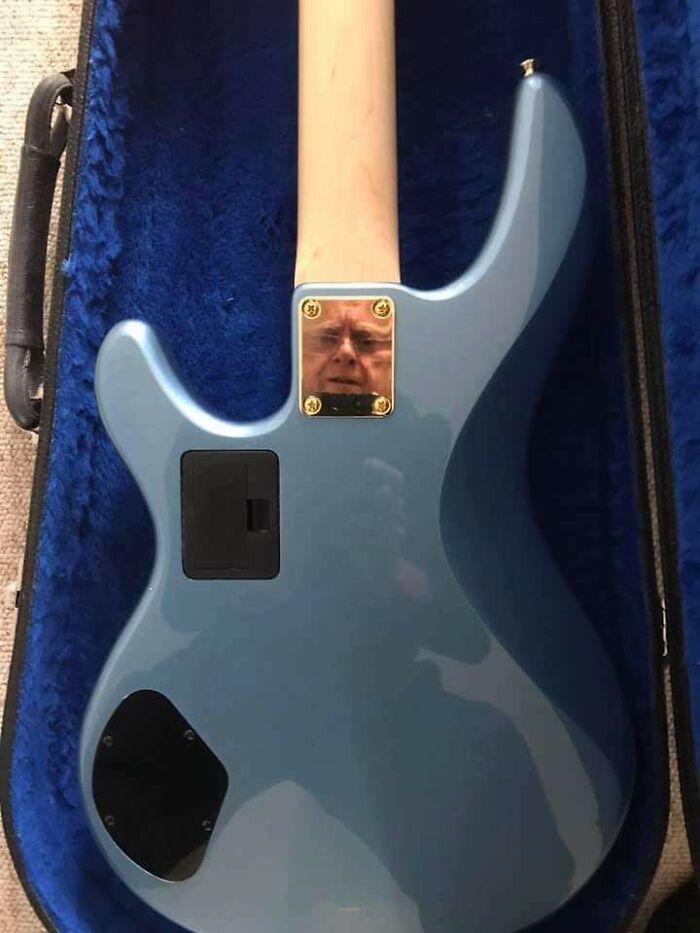 Blue electric guitar with an unusual reflection of a person’s face in the metal plate inside a guitar case.